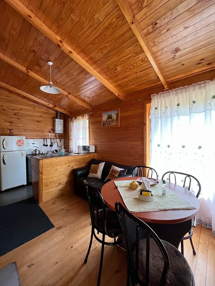Interior de cabaña de madera en San Sebastián: comedor, sillón y cocina equipada