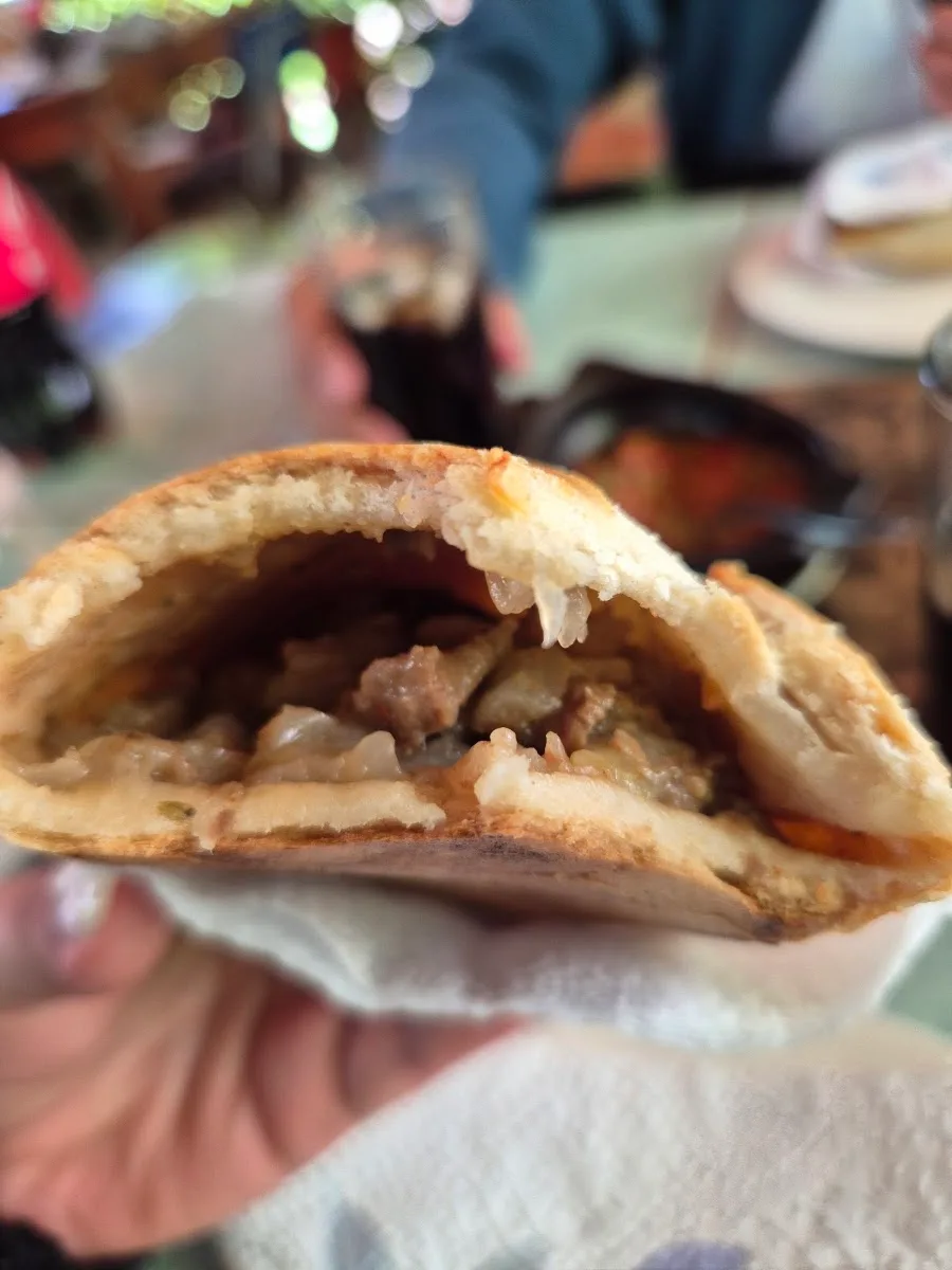 Empanada de pino recién abierta, con su relleno de carne y cebolla