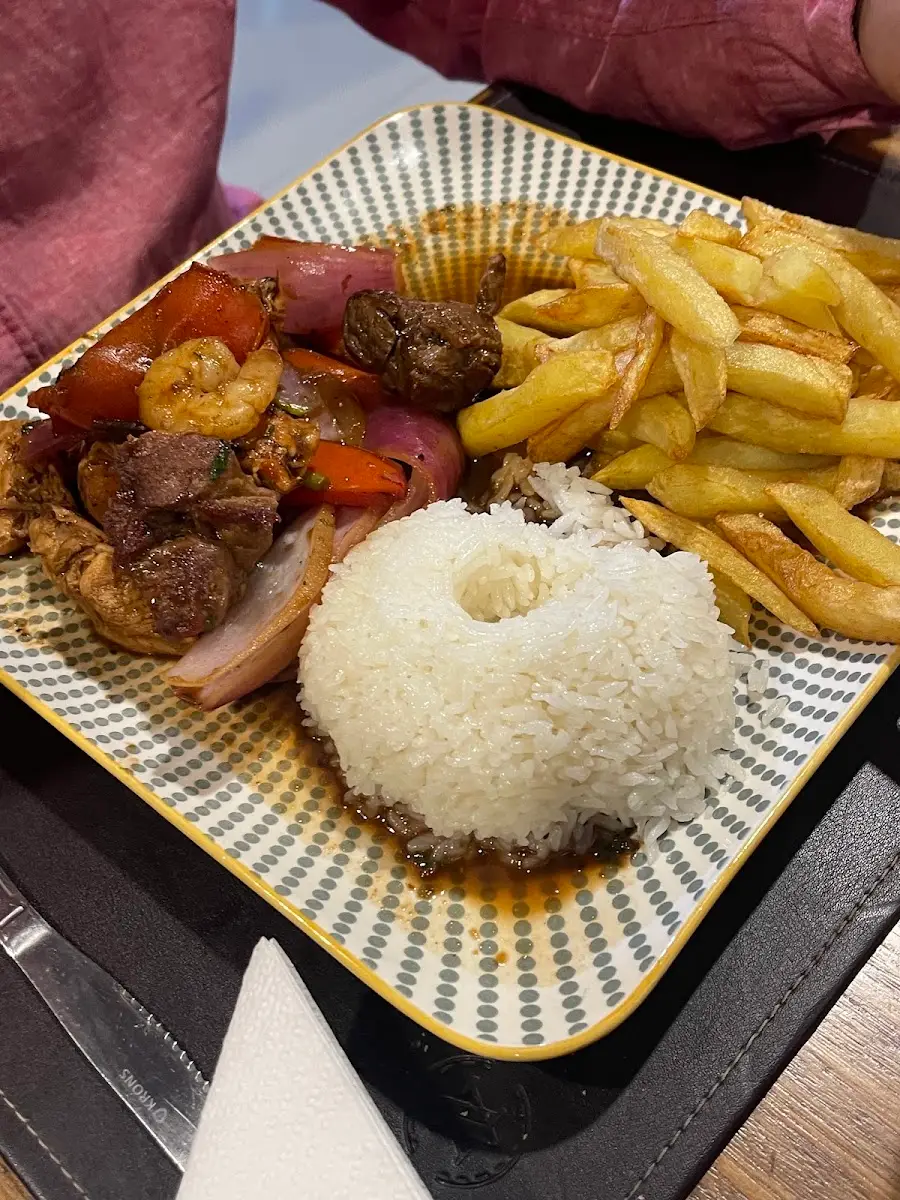 Lomo saltado con papas fritas y arroz servido en plato cuadrado