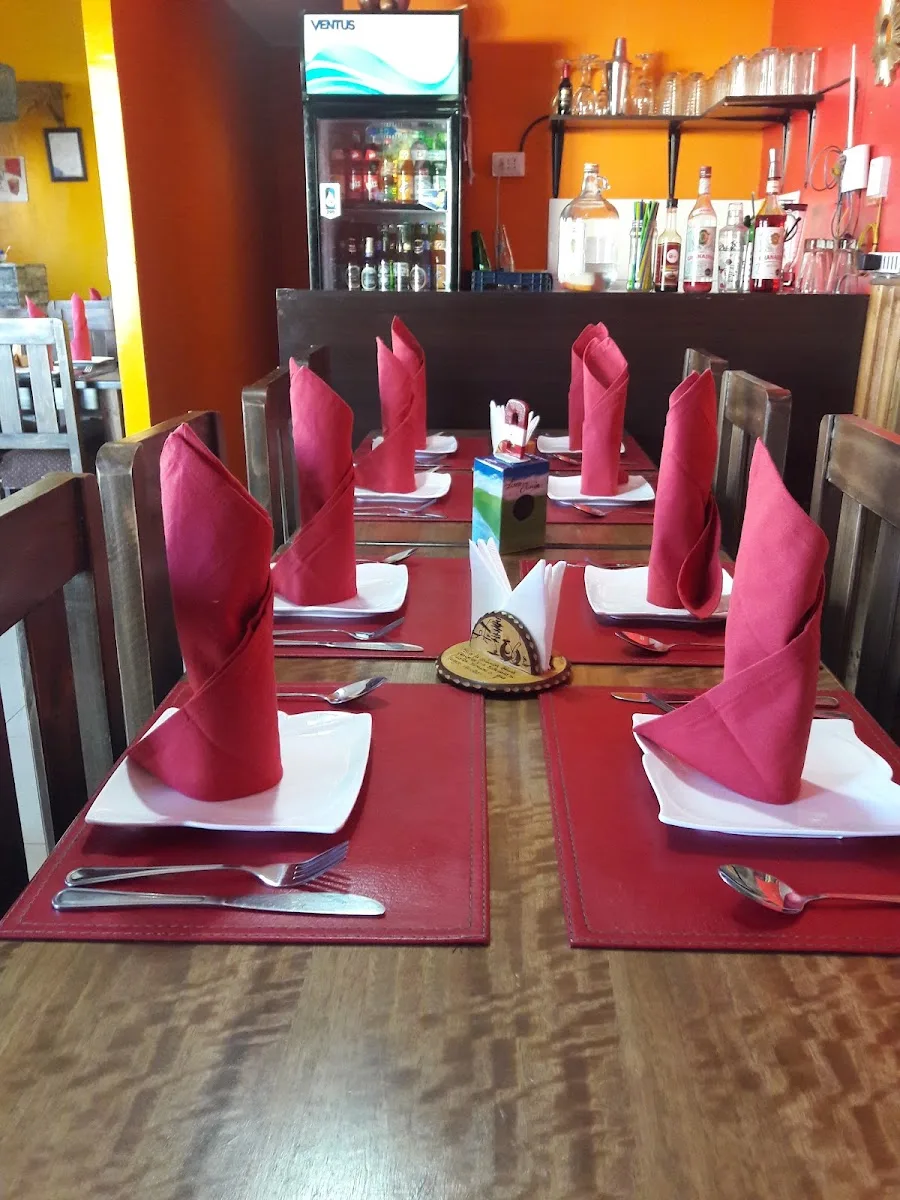 Mesas con servilletas burdeo y lámparas dentro del restaurante