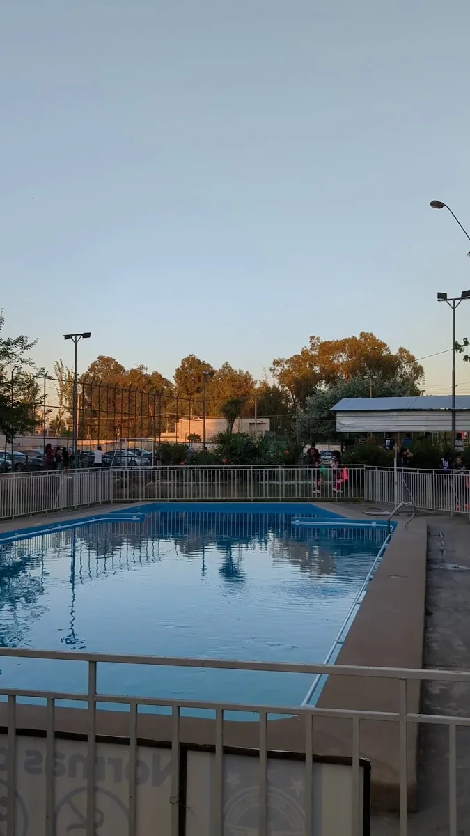 Piscina del complejo al atardecer detrás de la cerca