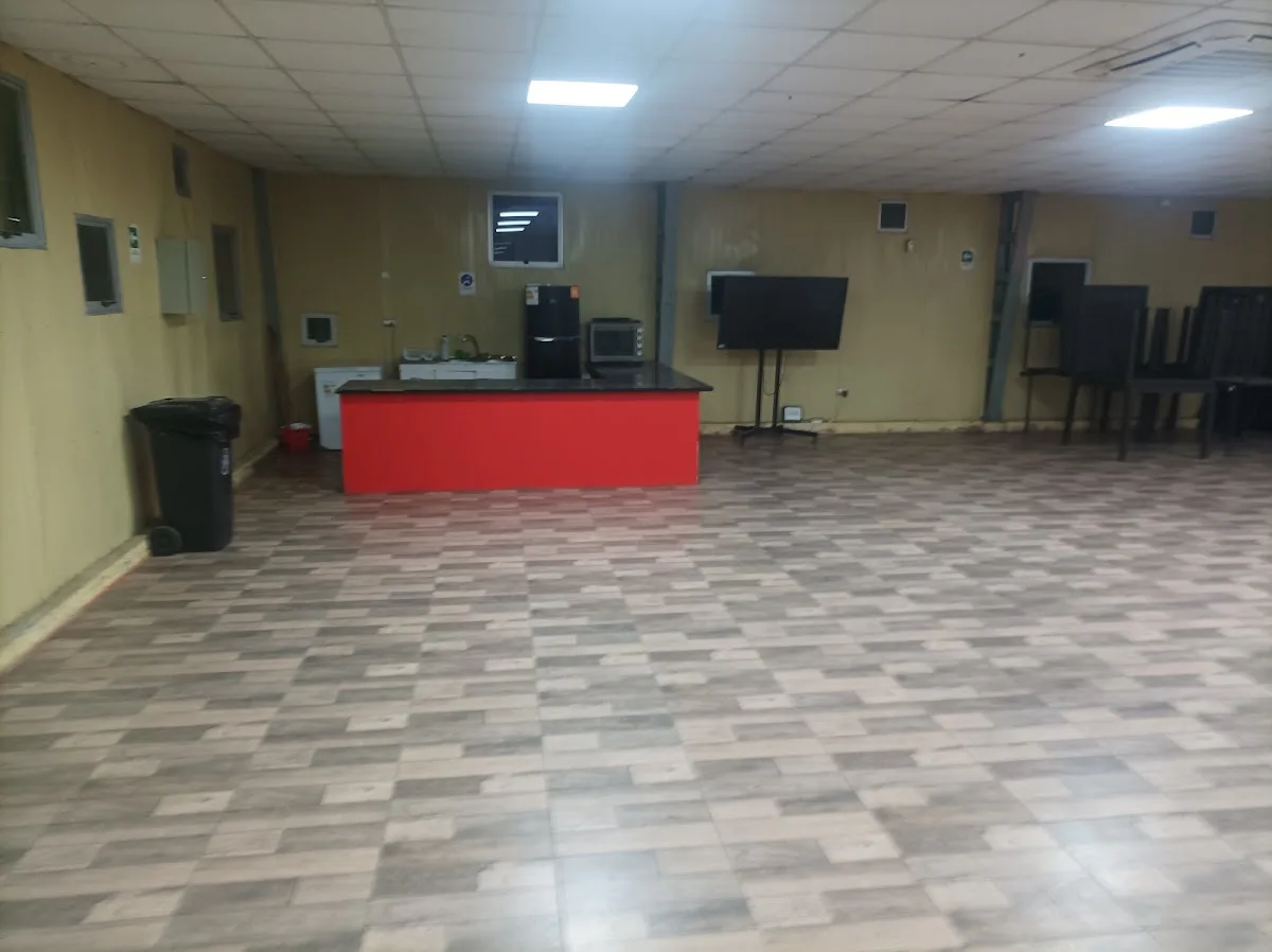 Sala multiuso interior con mesas, sillas y cocina
