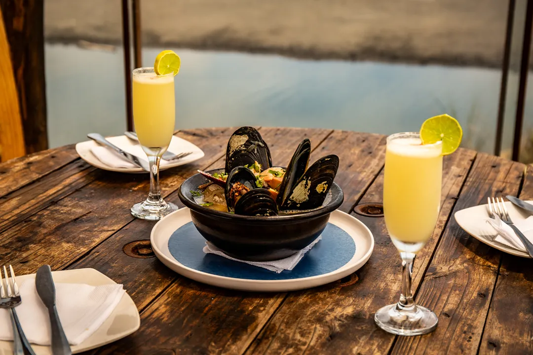 Choros a la parmesana y pisco sour servidos en la mesa