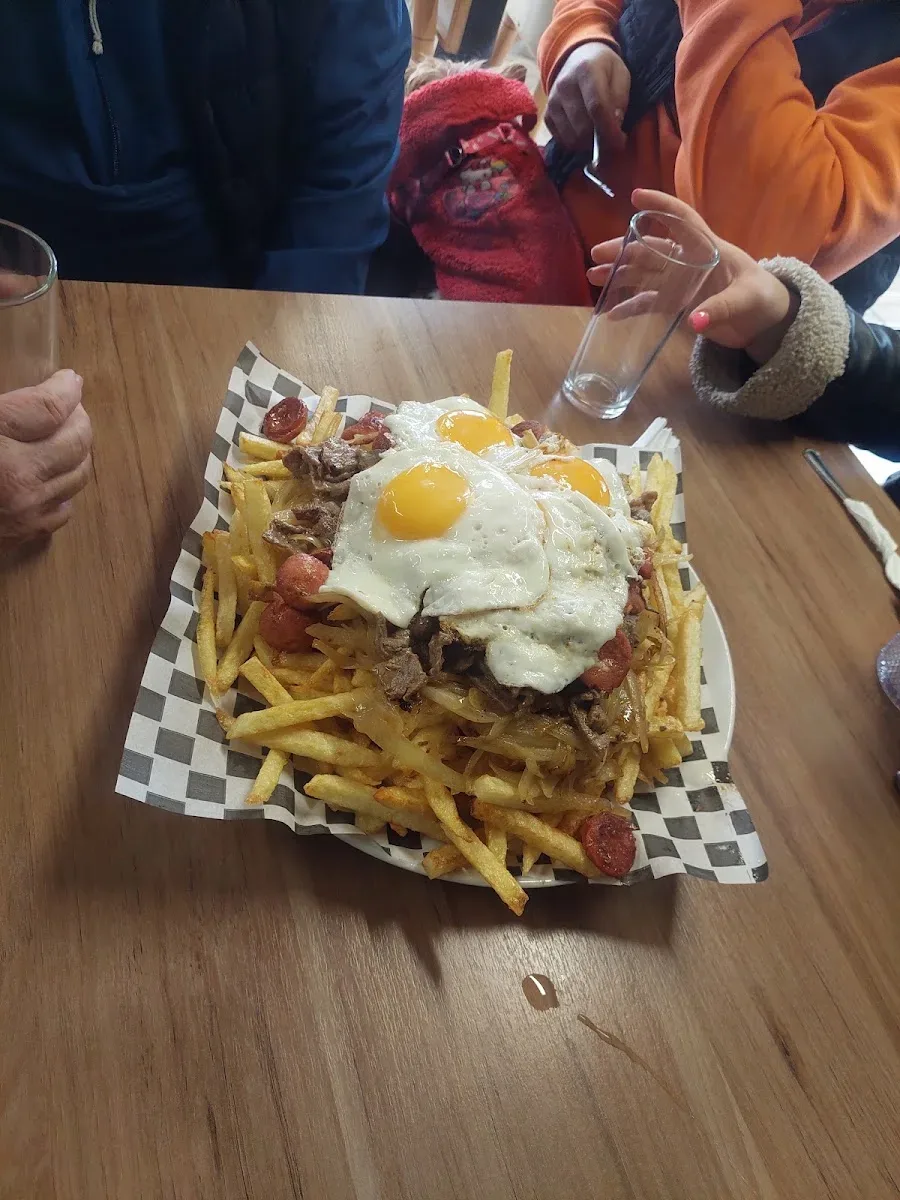 Chorrillana con huevo frito sobre papas en papel cuadriculado