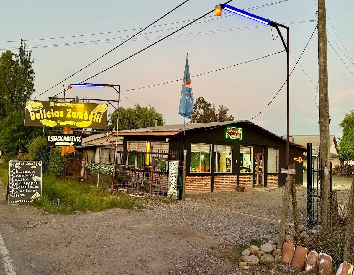 Fachada de día de Delicias Zambelli en El Plumero, Rauco, con el campanario de la iglesia al fondo