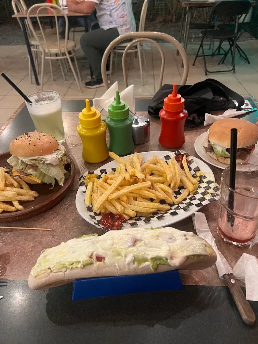 Mesa servida con hamburguesas, papas y un completo para dos personas