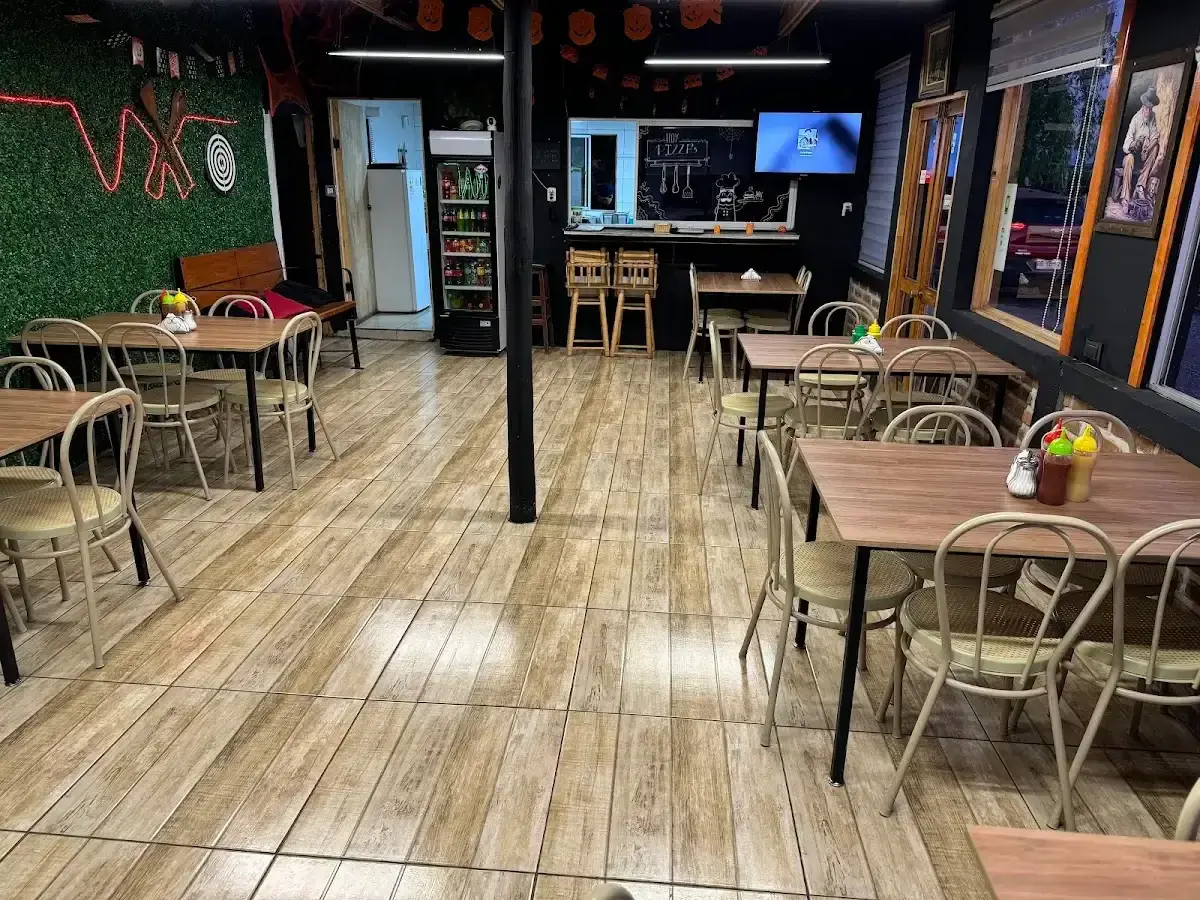 Salón interior de Delicias Zambelli con mesas y pizarrón