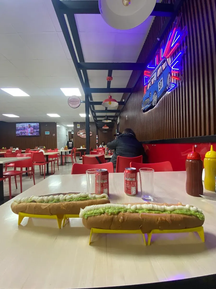Interior del local con mesas rojas y neón al fondo