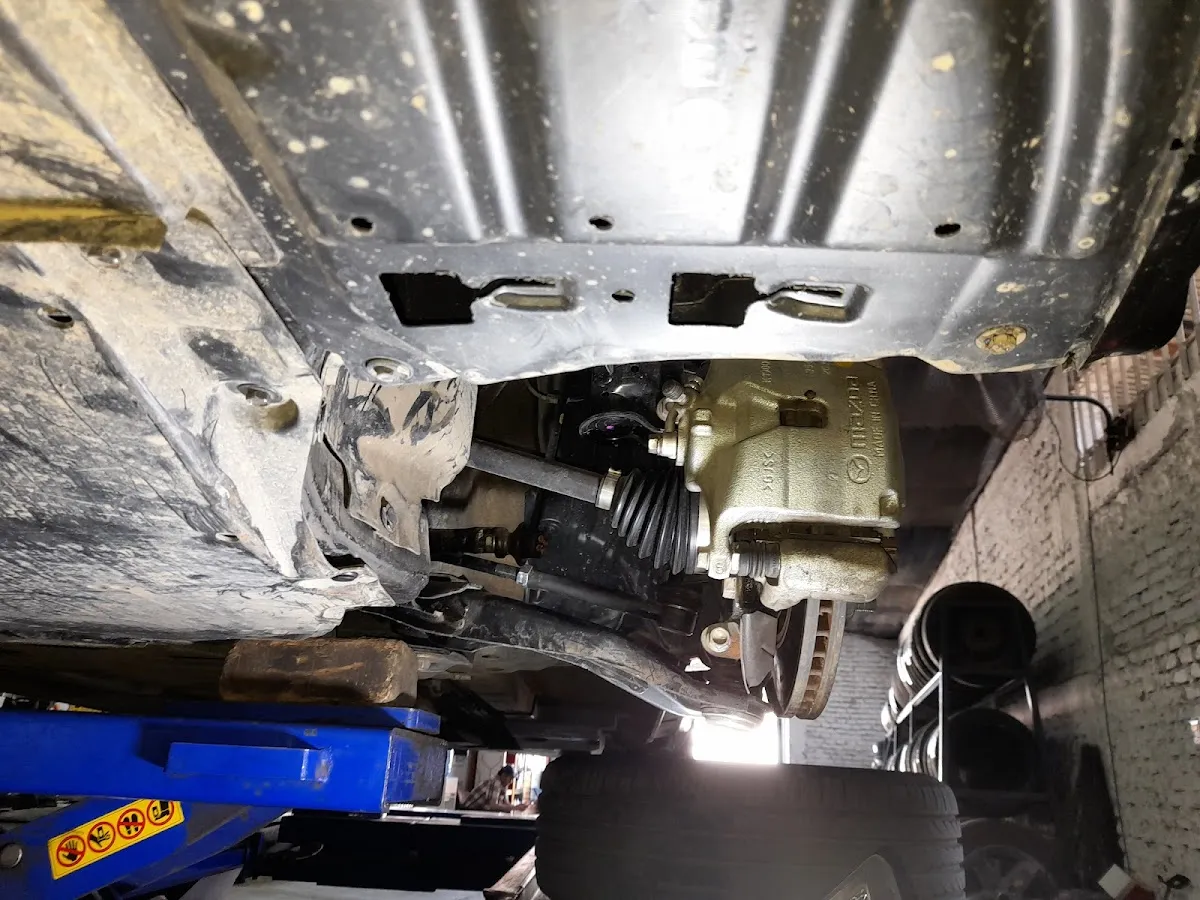 Auto sedán sobre el elevador de alineación con las pinzas de medición en las ruedas