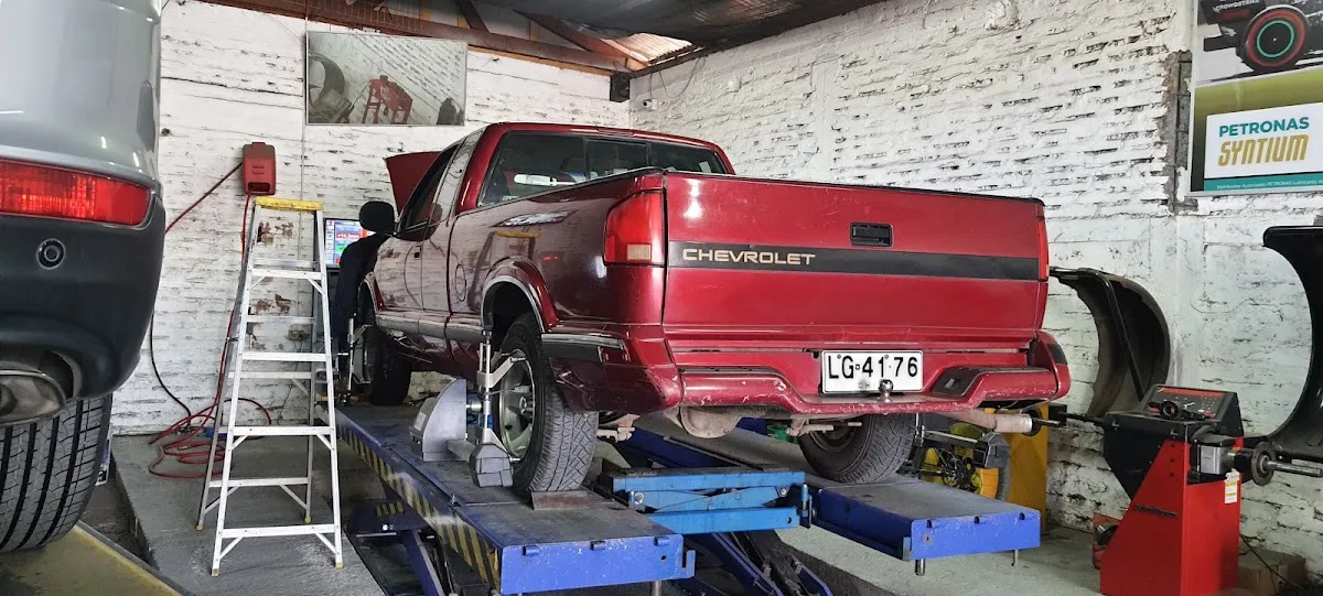SUV blanco sobre el rack de alineación dentro del taller Direcar