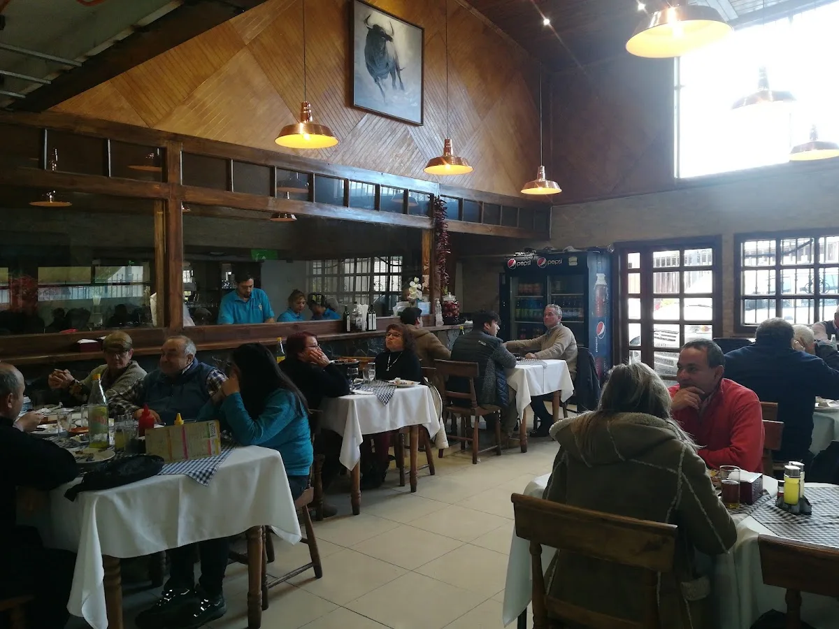 Comedor lleno de Donde Paulo: mesas con mantel, sillas de madera y el salón en hora de almuerzo