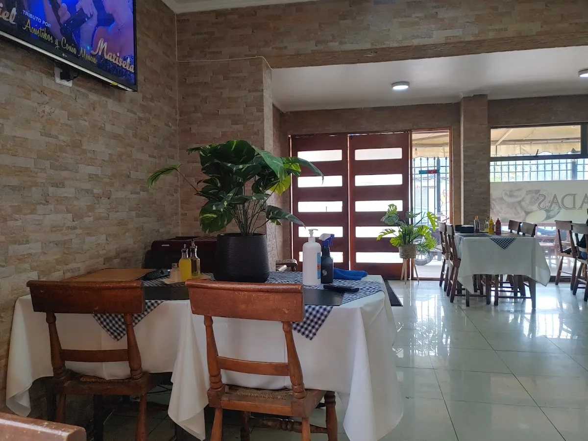 Nuevo salón de Donde Paulo: muro de piedra, mantel blanco y techo de madera