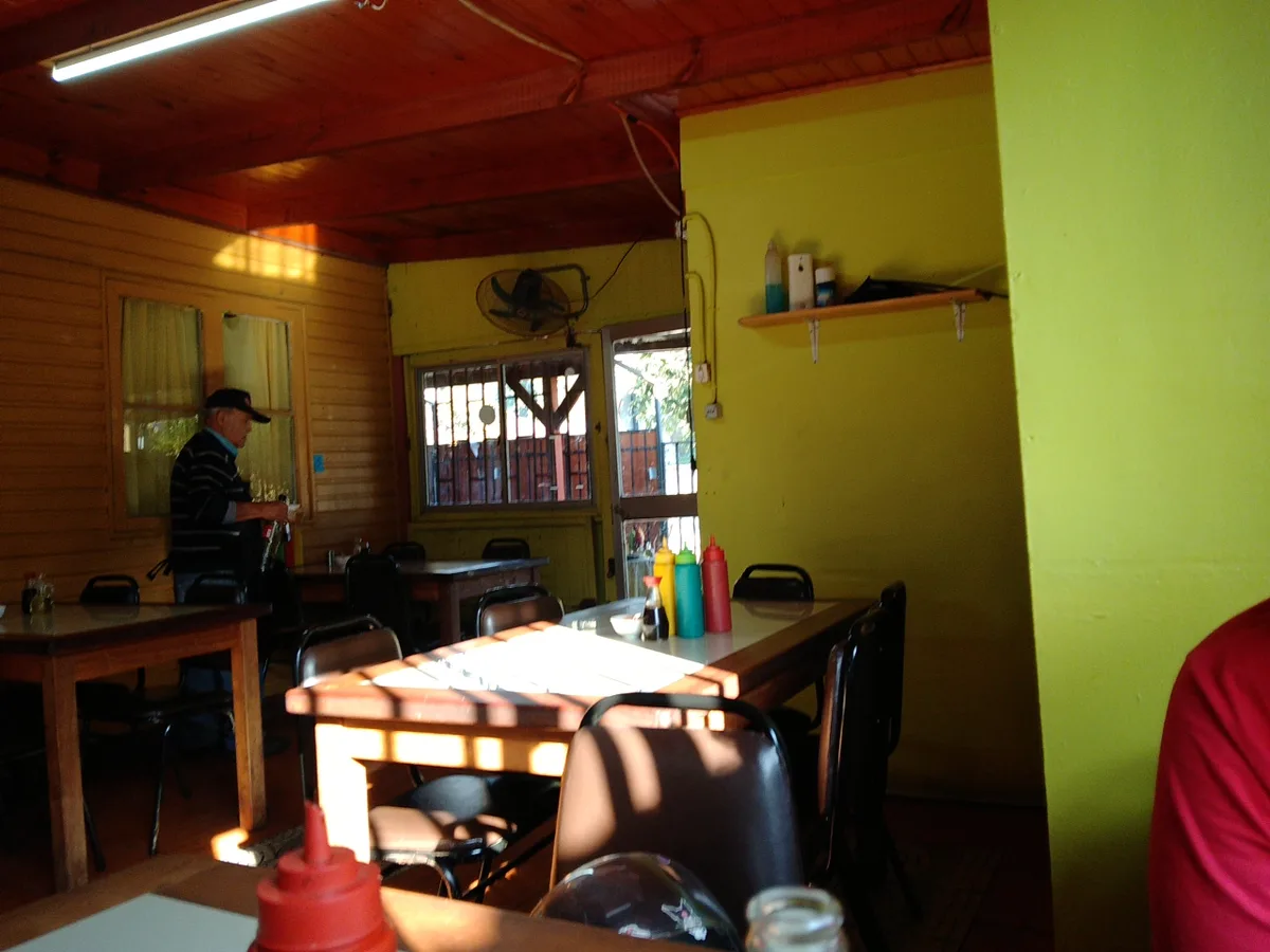 Interior amarillo del restaurante con mesas, cielo de madera y ventana al patio
