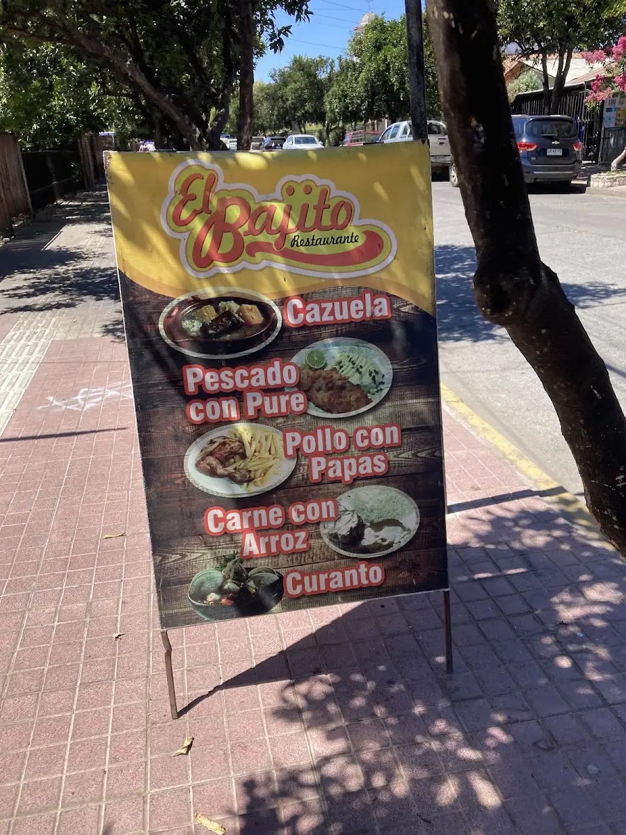 Letrero amarillo de El Bajito en la vereda con el menú del día pintado