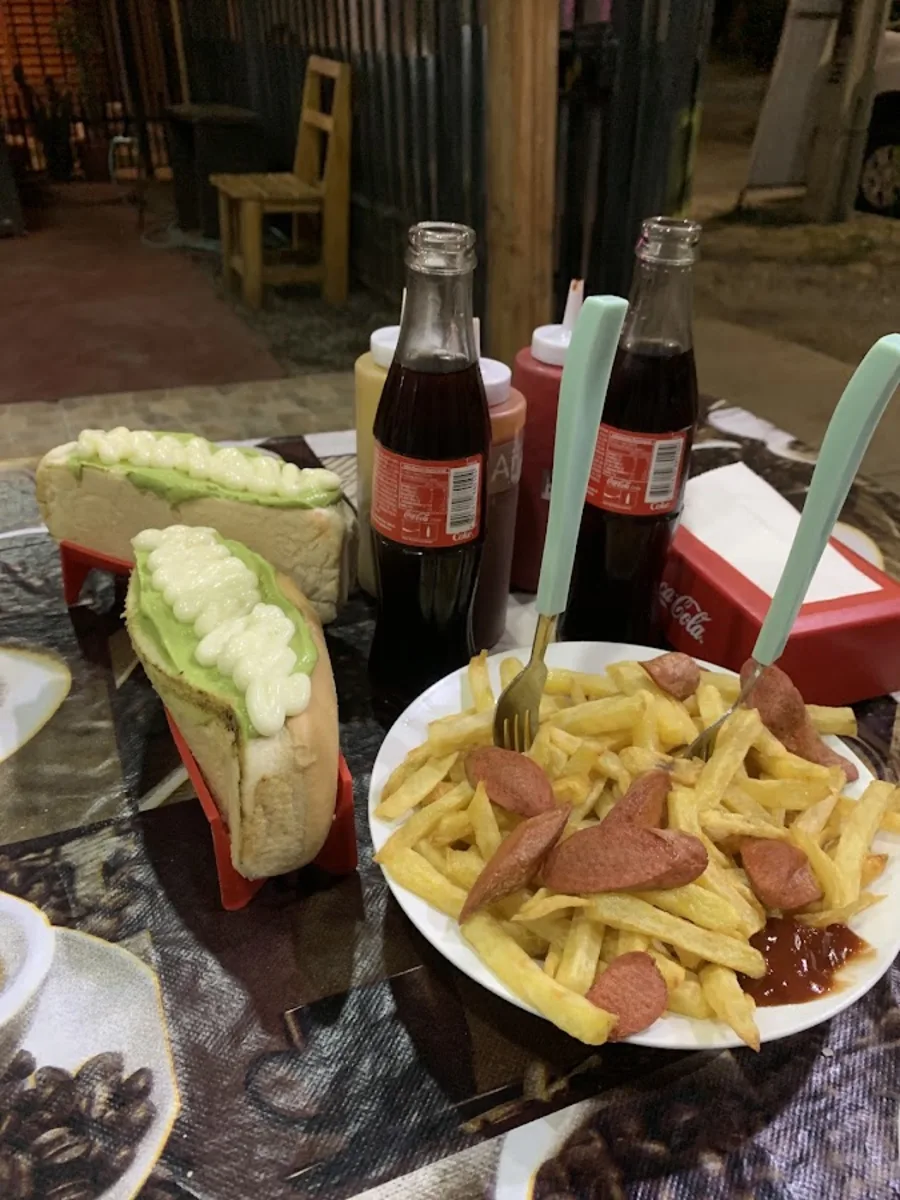 Mesa con completos, salchipapas y bebidas en El Bajón del Barny
