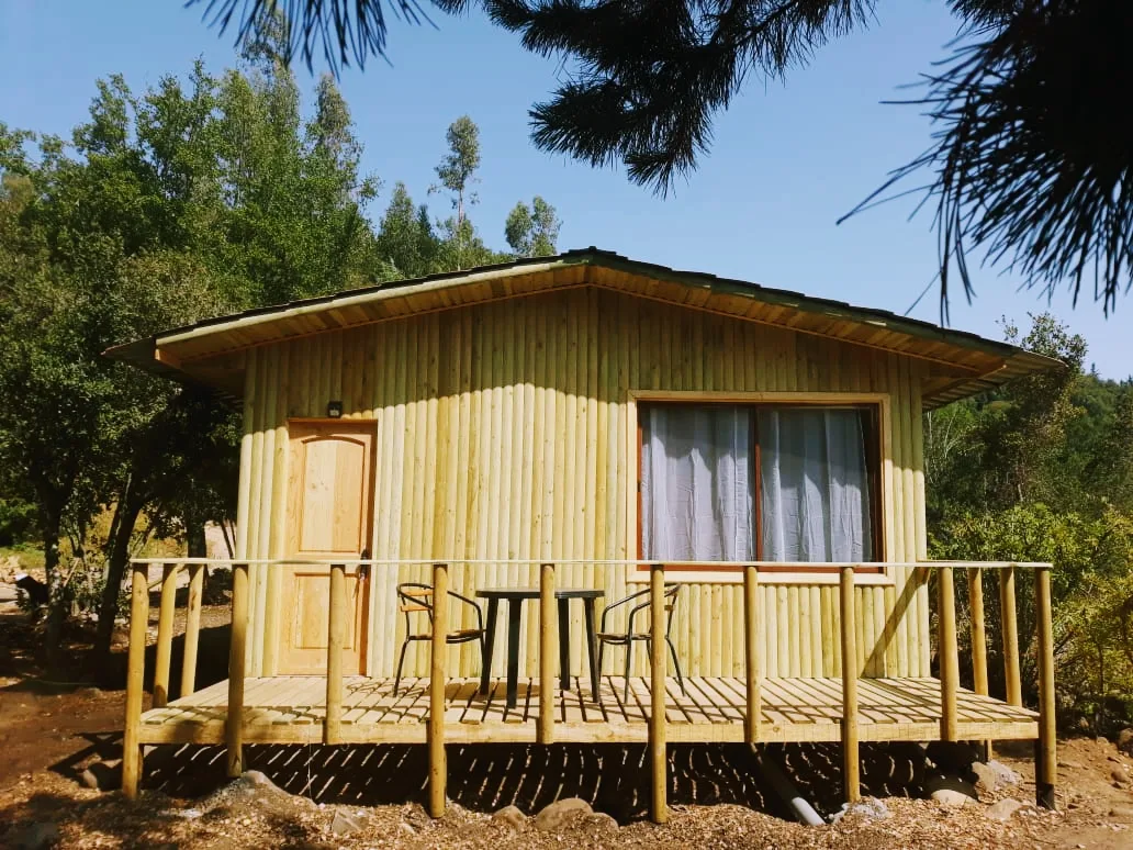 Cabaña de madera con terraza entre árboles en El Fogón