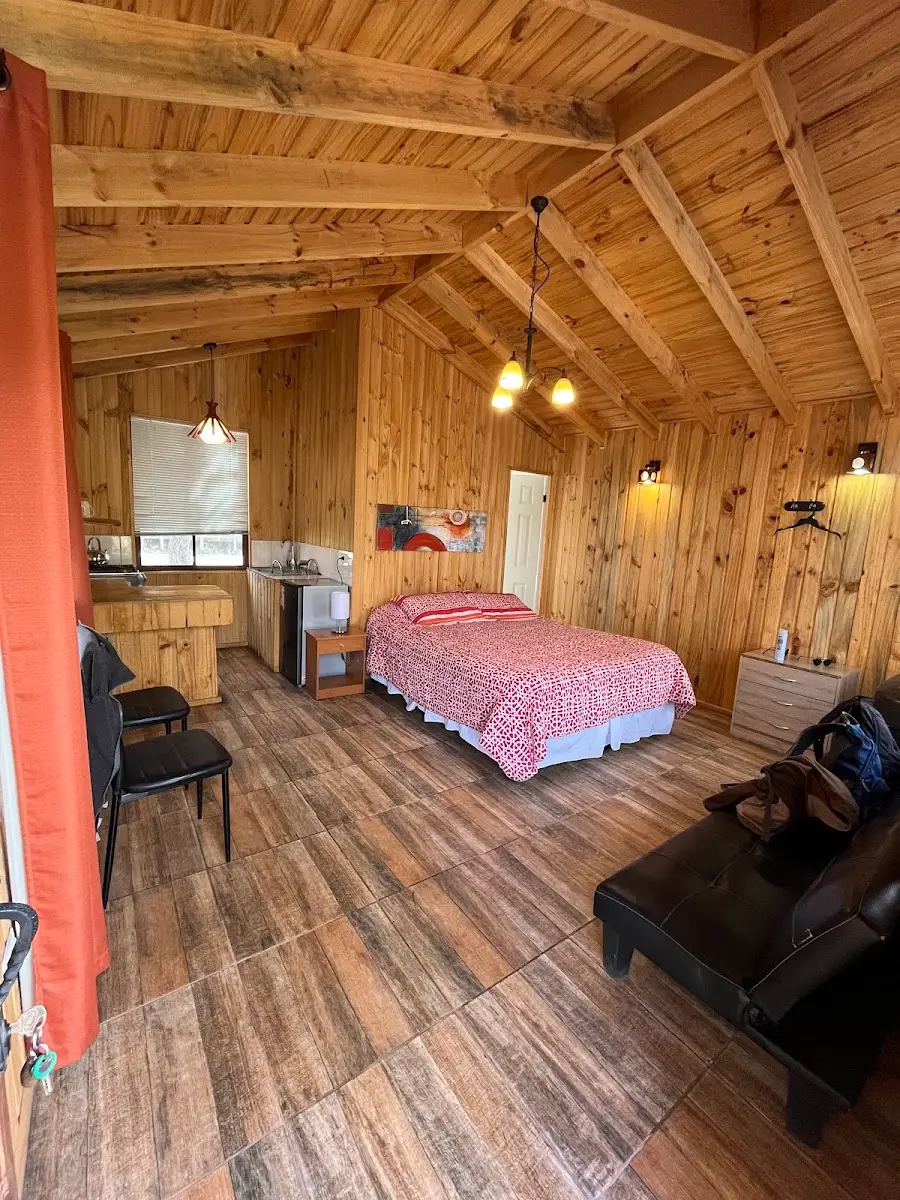 Interior de cabaña con cama y kitchenette en El Fogón