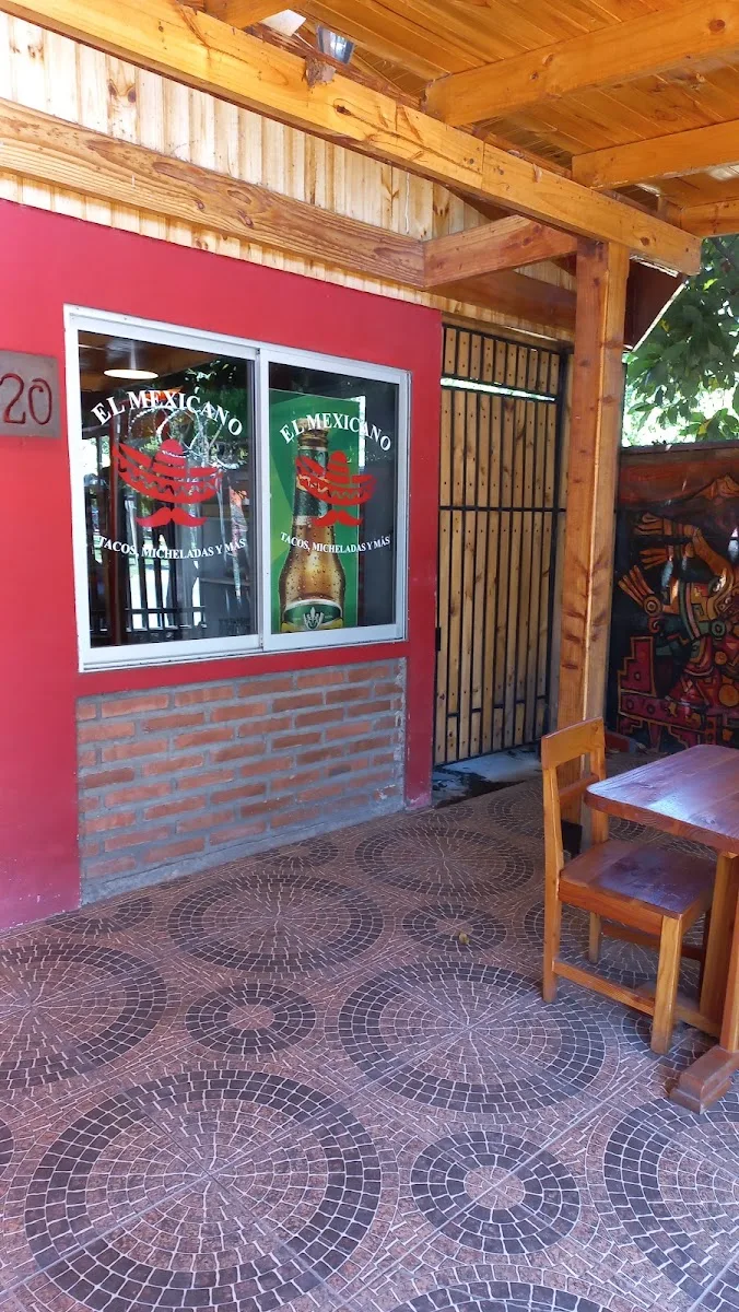Terraza techada de El Mexicano: muro rojo, piso de mosaico y el logo en el ventanal