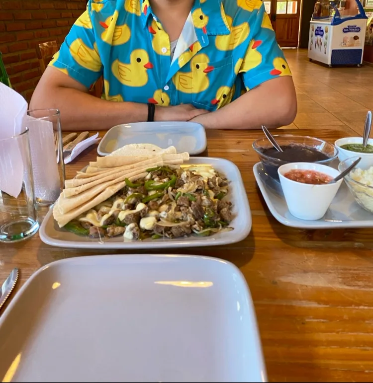 Alambre servido en la mesa con tortillas y tres salsas