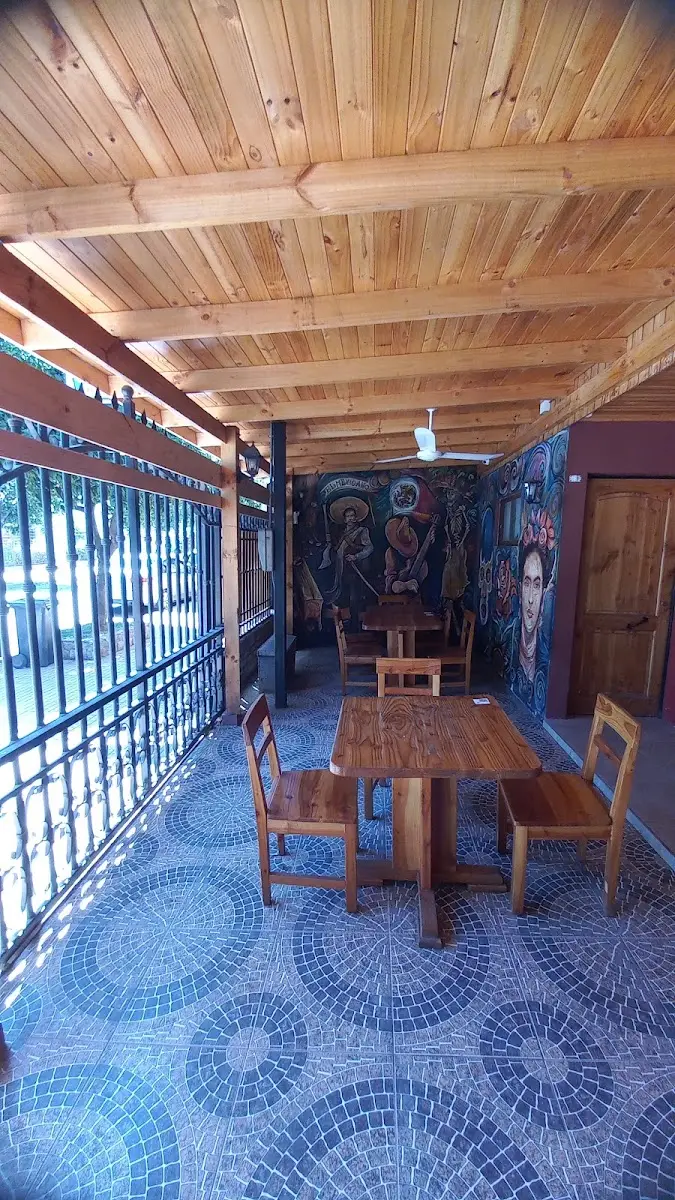 Corredor interior con techo de madera, piso de mosaico azul y murales