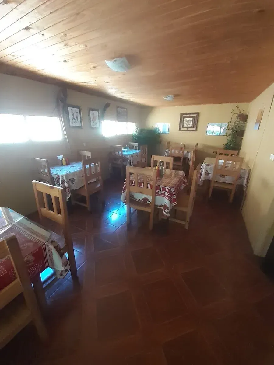 Comedor interior de El Pollo Farsante con mesas de madera y paredes ilustradas