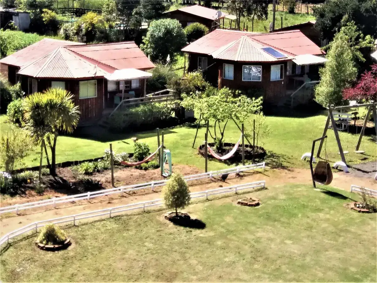 Jardines y casita de juegos entre árboles en el parque de cuatro hectáreas de El Quincho Espacio Colibrí
