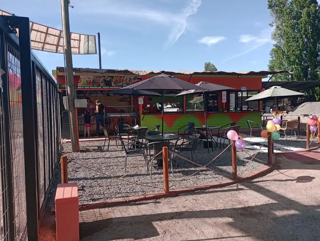 Entrada de El Rincón del Sabor con sombrillas rojas y mesas en la terraza