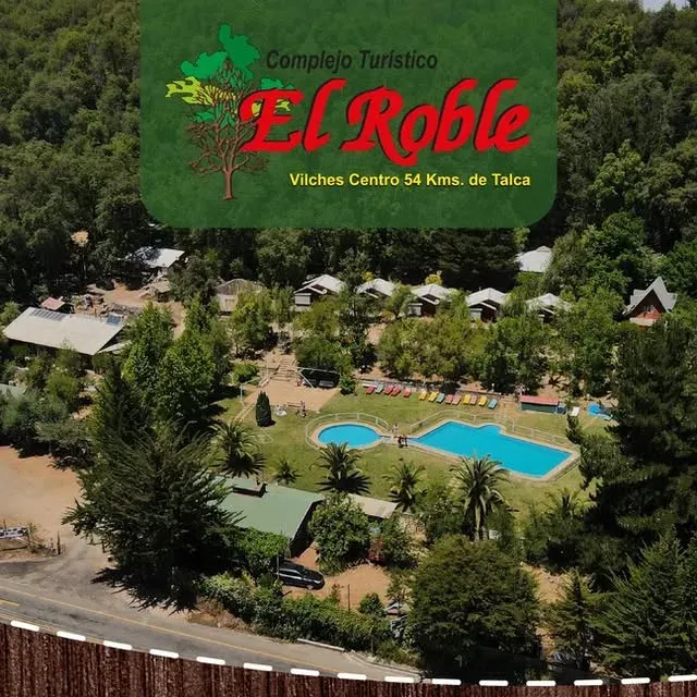 Portón de entrada del Complejo Turístico El Roble con su logo, letreros de restaurant y masaje & spa