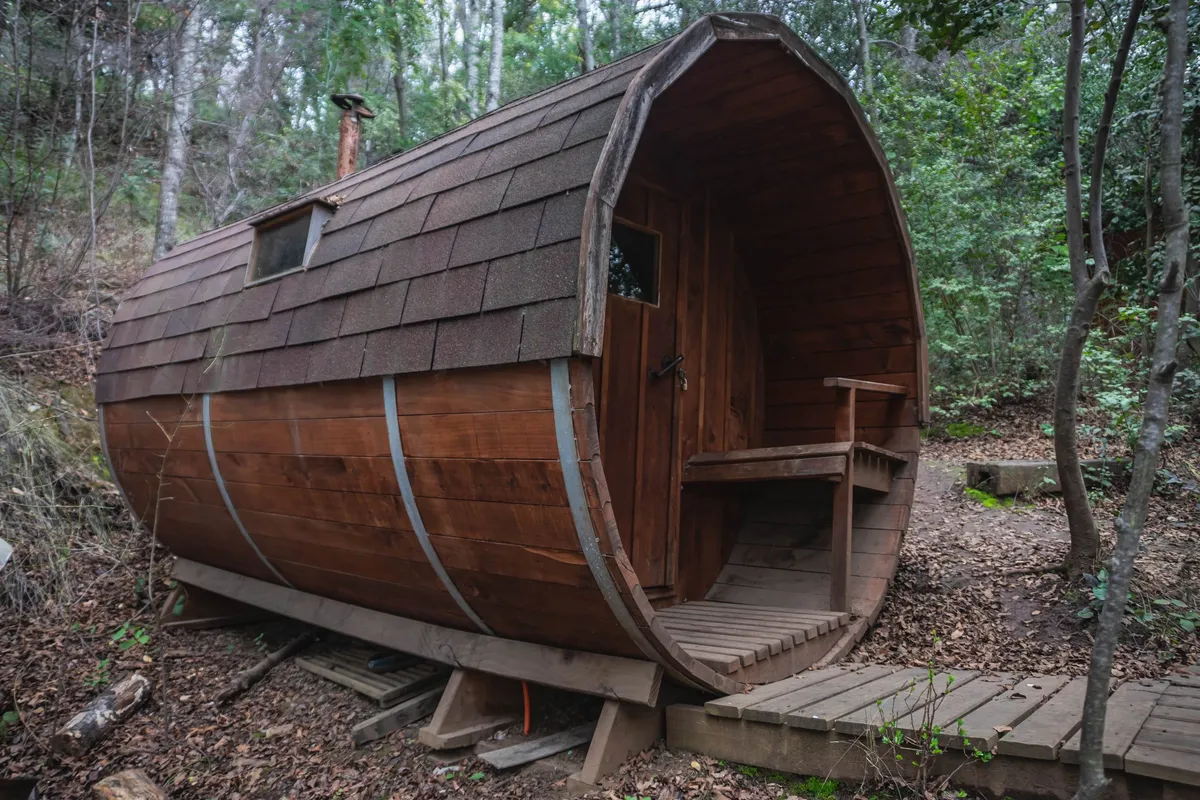 Sauna de barril de madera instalado entre los árboles del complejo