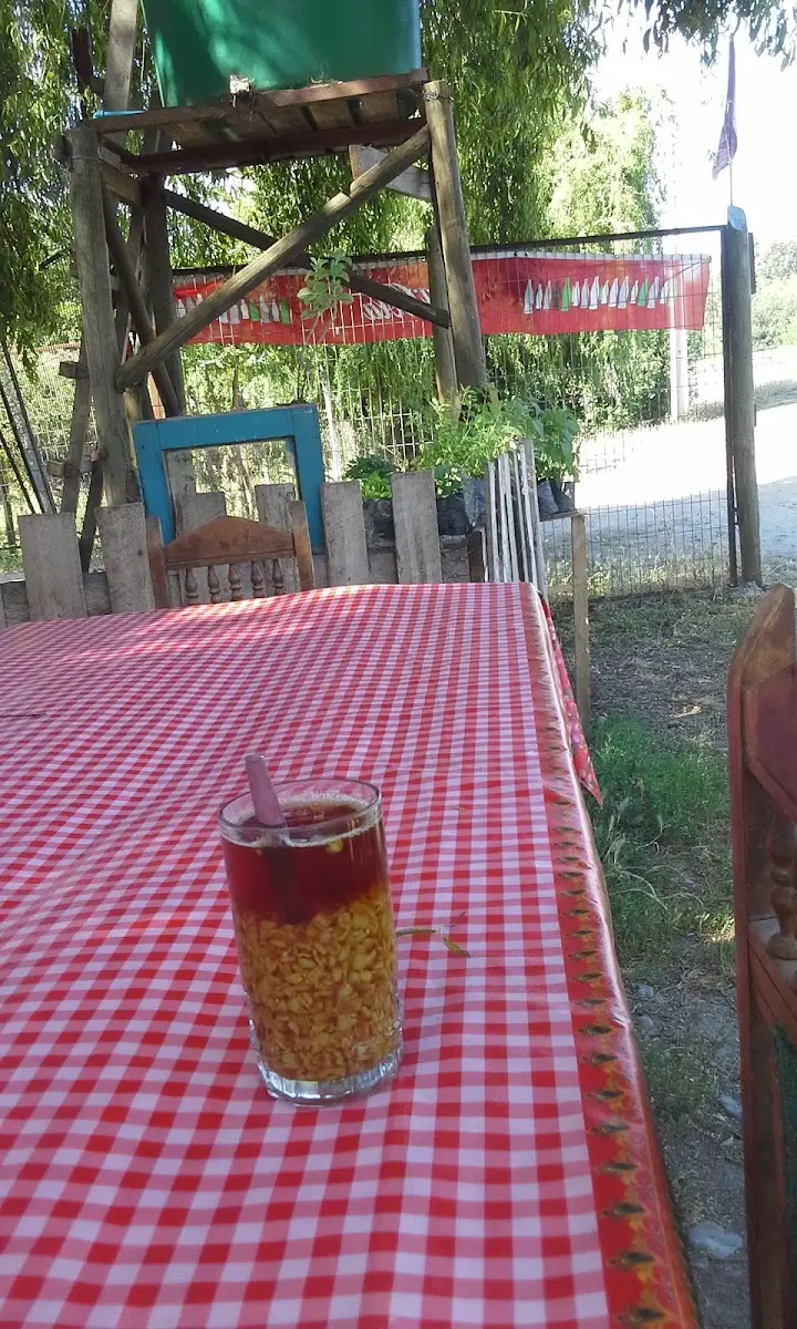 Vaso de mote con huesillo sobre una mesa con mantel a cuadros rojos de El Sauce