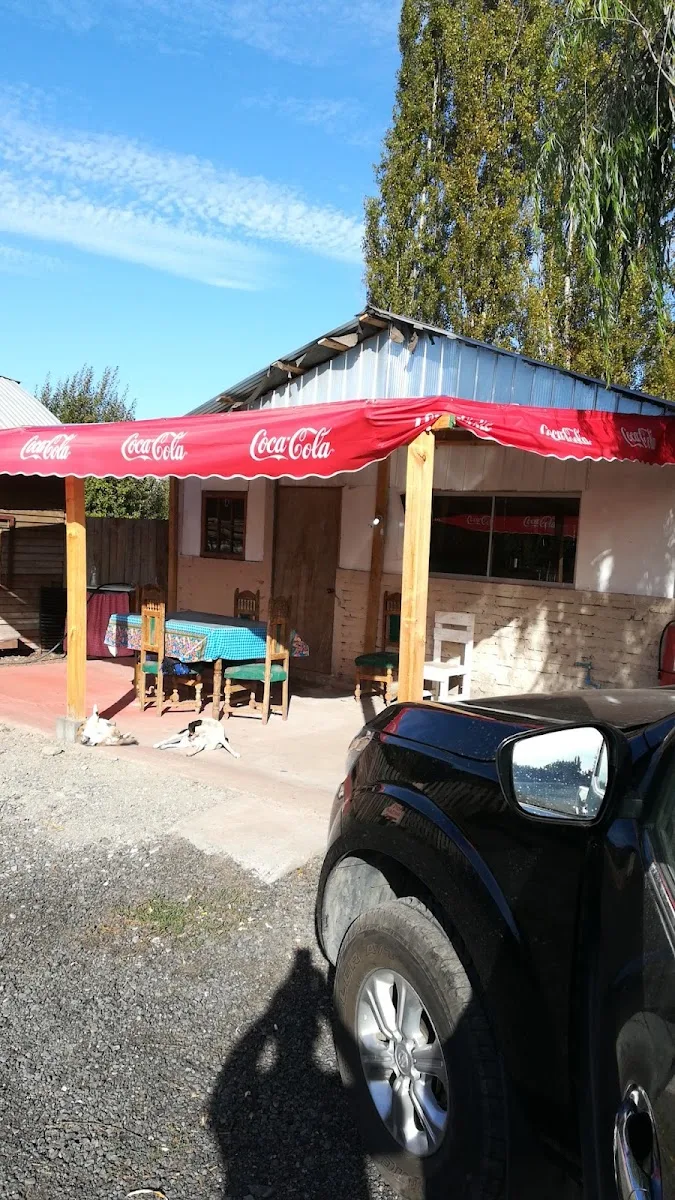 Fachada de El Sauce con el toldo rojo visto desde la ruta