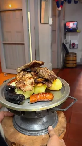 Parrillada de la casa servida en su fuente de mesa: lomo, chorizo, longaniza, prieta y papas cocidas