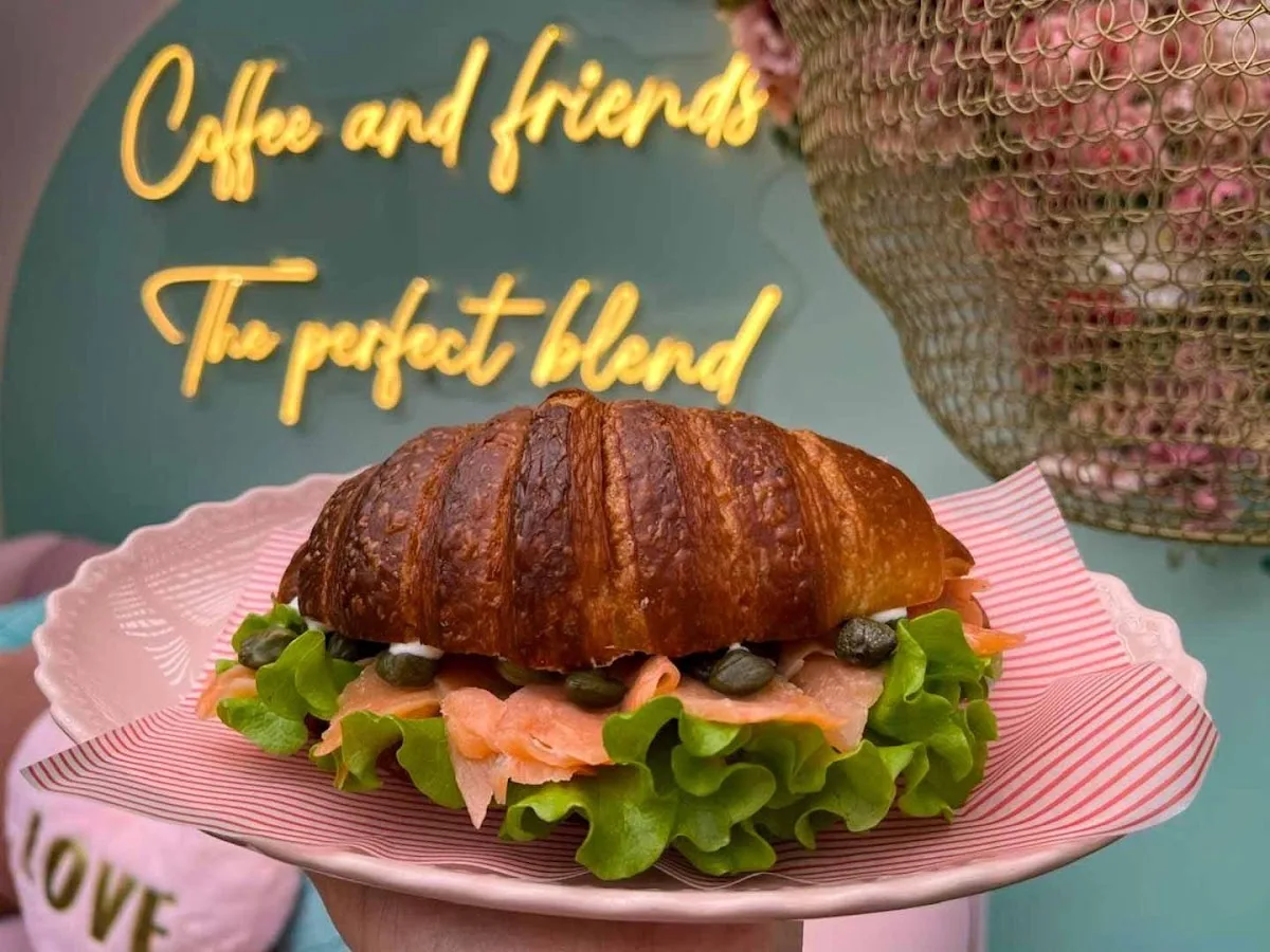 Croissant sandwich con palta y huevo en plato rosado