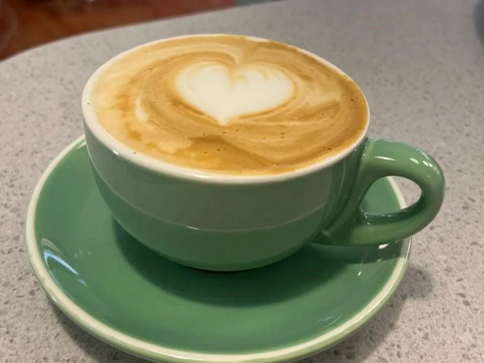 Latte con arte servido en taza verde salvia de Emilia