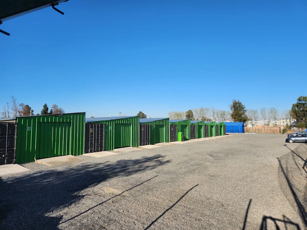 Fila de módulos verdes numerados con puertas de contenedor sobre gravilla — foto de la ficha de Google