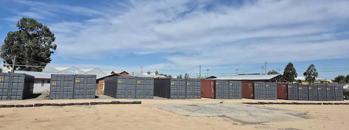 Panorámica del patio de Espacio Unihue: fila de contenedores grises numerados D1 a D15 sobre gravilla — foto de la ficha de Google