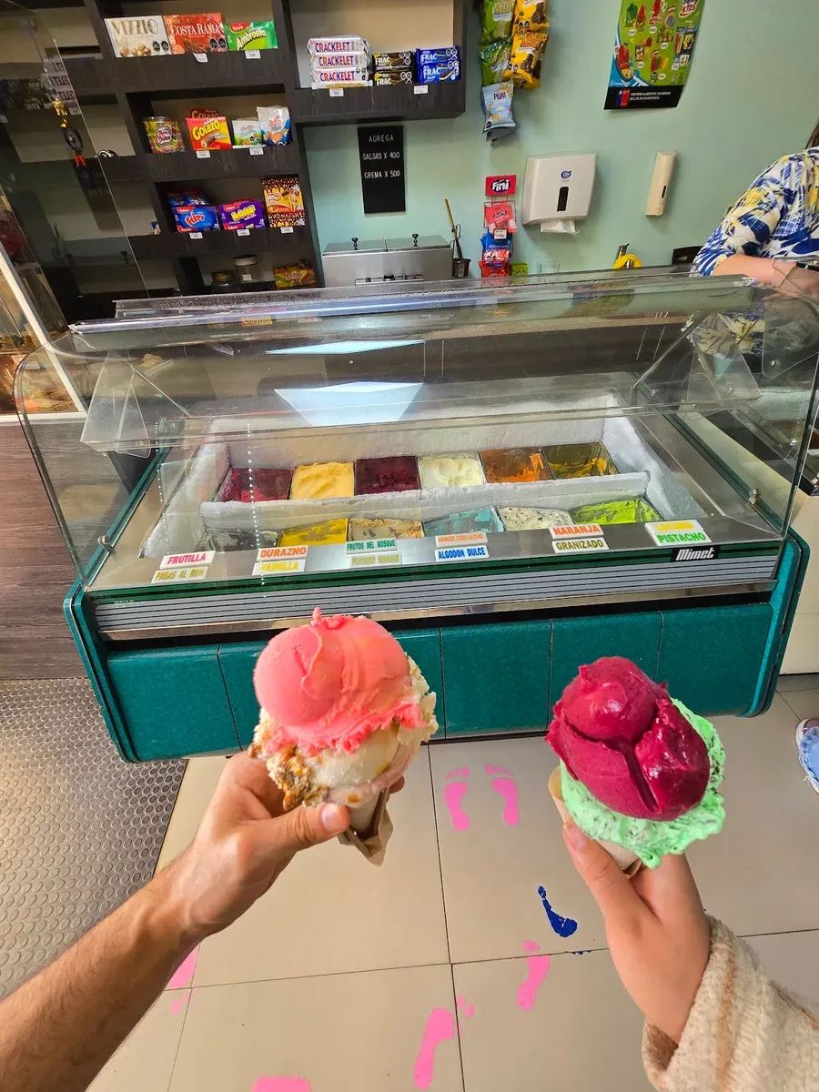 Dos conos de helado, uno rosado y uno rojo, en la vitrina