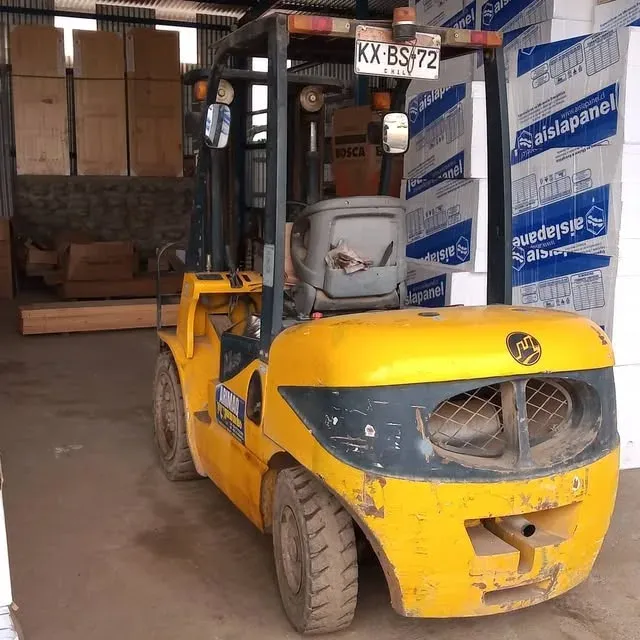 Grúa horquilla amarilla cargando pallets de paneles