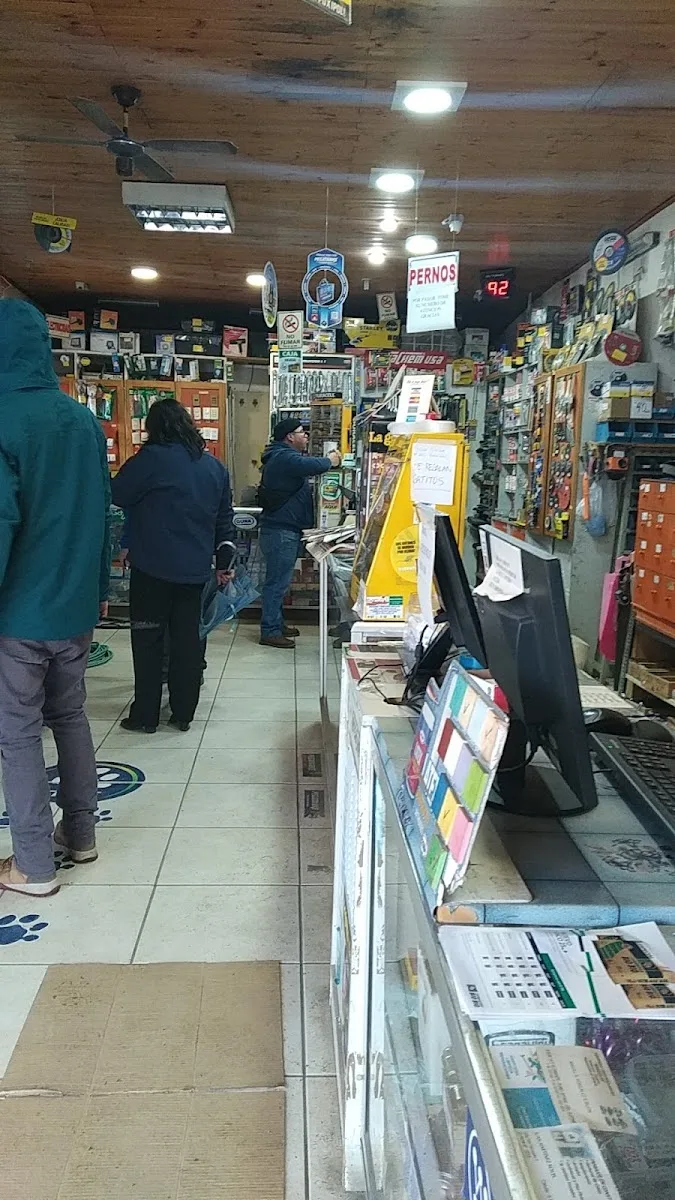 Interior de FerriMas: pasillo con repisas de madera llenas de herramientas y clientes comprando