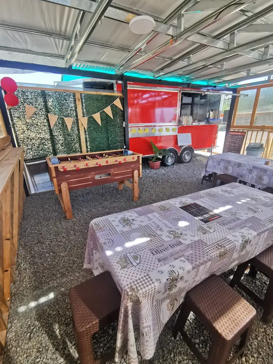 Patio techado del food truck con mesas, un taca-taca y banderines de colores