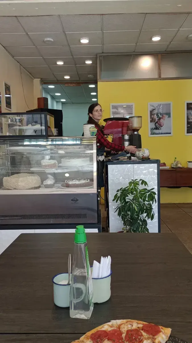Interior de Frontera Café en la Galería Meval, con su vitrina de tortas y pared amarilla