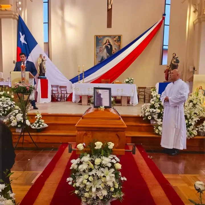 Interior de iglesia durante una misa de funeral con arreglos florales blancos