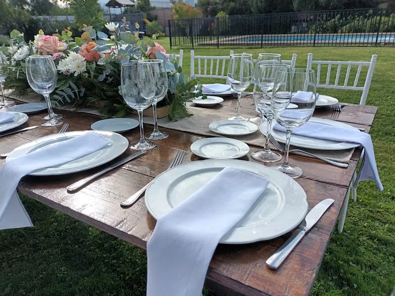 Mesa de evento montada por Gacitúa Producciones y Eventos en un patio, con loza blanca y copas