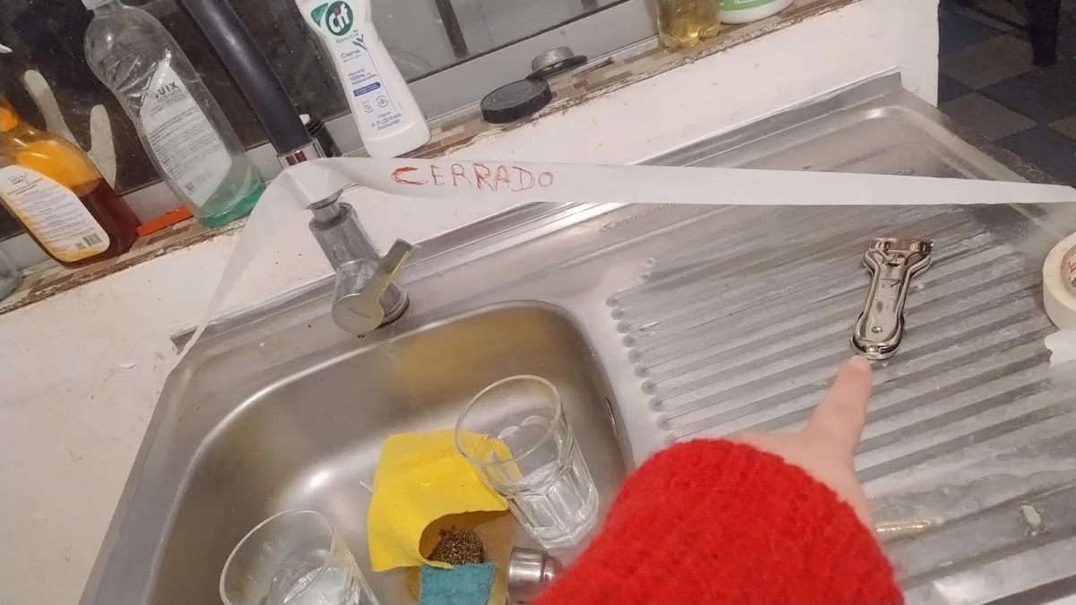 Mano marcando la llave de un lavaplatos en pleno trabajo