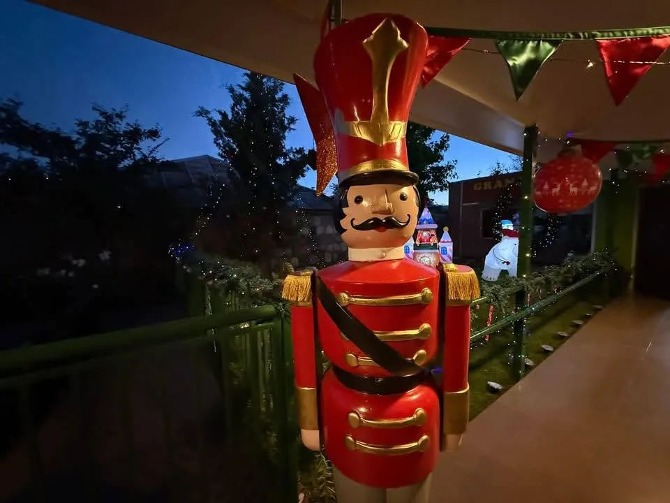 Entrada del jardín de noche, con el letrero Granjeritos iluminado y un soldado decorativo