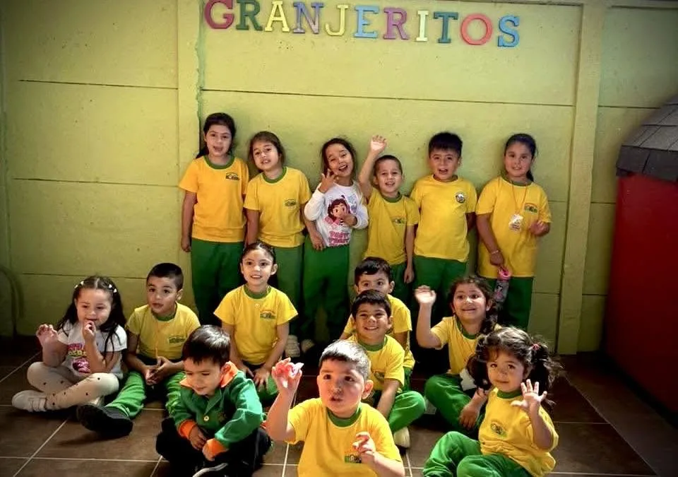 Grupo de párvulos con sus profesoras de polera amarilla dentro de la sala