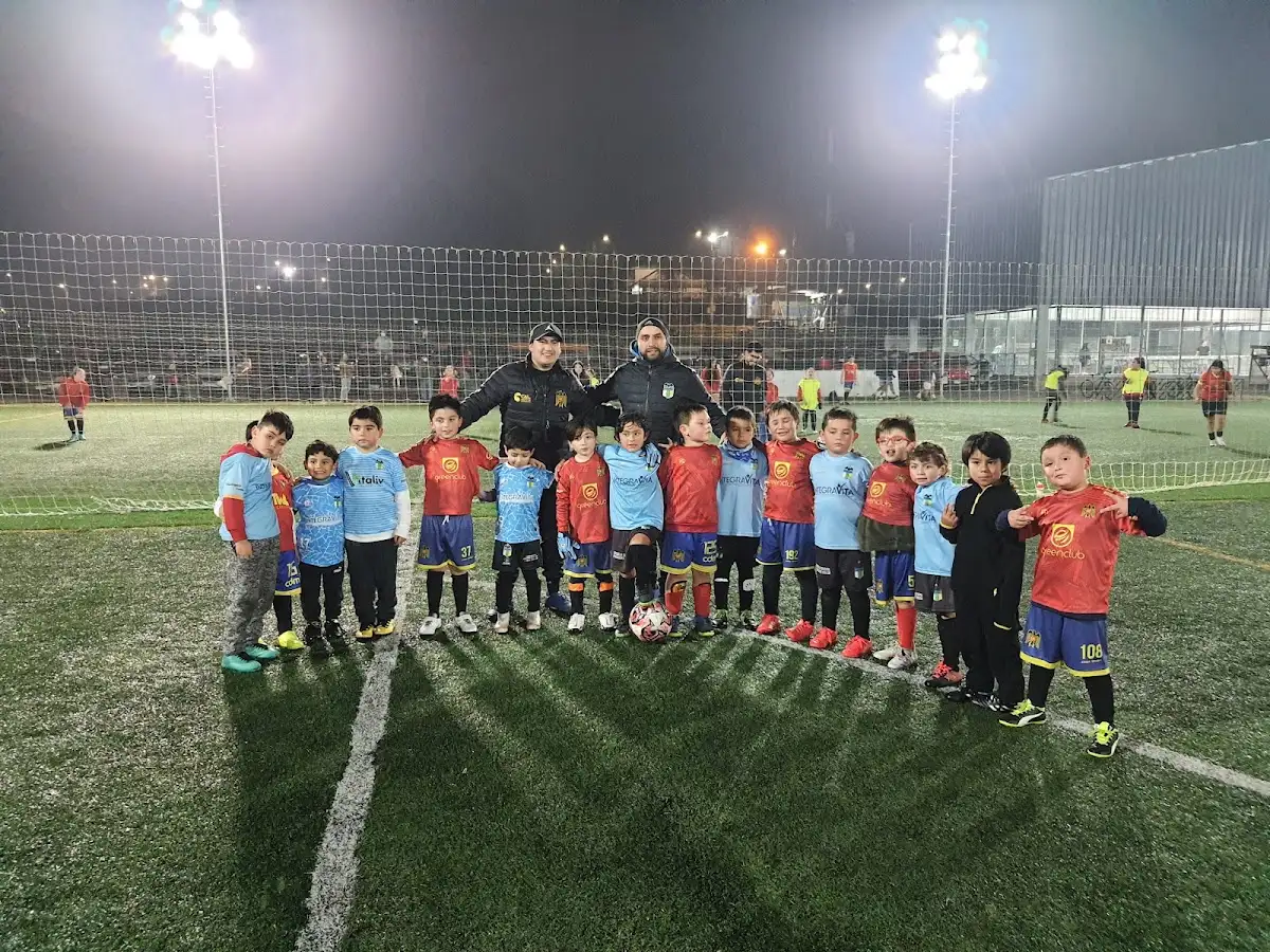 Grupo de niños de la escuela de fútbol de Greenclub en la cancha de noche