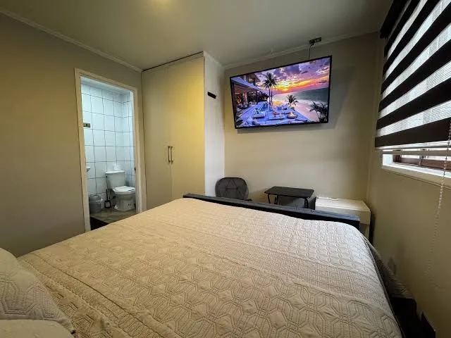 Habitación con cama, televisión encendida y vista al baño privado