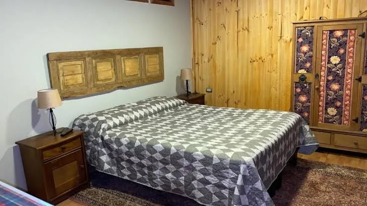 Habitación con cama de cubrecama estampado, velador y armario de madera