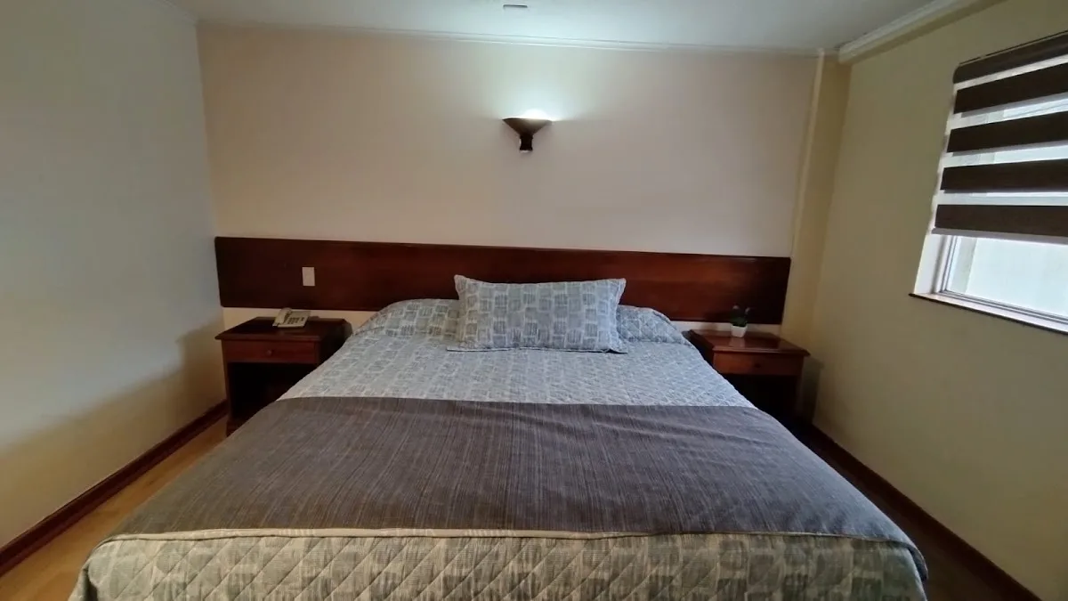 Habitación matrimonial del hostal con cama de dos plazas y respaldo de madera